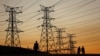 FILE - Locals walk past electricity pylons in Soweto, South Africa, July 3, 2022. Matshela Koko, the former head of the country's power provider Eskom has been charged with multiple counts related to corruption, fraud and money laundering.