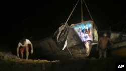 Un barco con varios cadáveres es sacado del agua por las autoridades en el puerto de Vila do Castelo en Braganca, Brasil, la madrugada del lunes 15 de abril de 2024. 