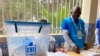 Delegado de mesa olha para urna com os boletins de voto