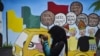 Seorang remaja perempuan tampak menggunakan ponselnya di area depan mural kampanye Pemilu 2019 yang terpasang di sebuah lokasi di Banda Aceh, pada 17 Maret 2019. (Foto: AFP/Chaider Mahyuddin)