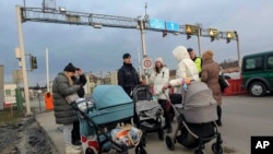 Refugiados ucranianos son asistidos por la policía fronteriza polaca en el cruce fronterizo de Medyka, Polonia, el sábado 26 de febrero de 2022. (Foto AP/Visar Kryeziu)
