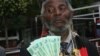 Holding bills of new Zimbabwean money, a man welcomes the introduction of 'bond notes' saying the move will ease cash shortages in the country, in Harare, Zimbabwe, Nov. 28, 2016. (S. Mhofu/VOA)