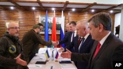 Delegacioni ukrainas (majtas) dhe ai rus (djathtas) shtrëngojnë duart (3 mars 2022)