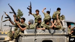 Shi'ite fighters ride on a patrol truck as they chant slogans during a tribal gathering showing support for the Houthi movement in Sana'a, Yemen, Dec. 14, 2015..