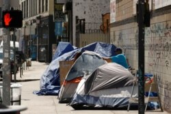 FILE - Tents and tarps erected by homeless people are shown along sidewalks and streets in a portion of downtown Los Angeles, June 28, 2019.