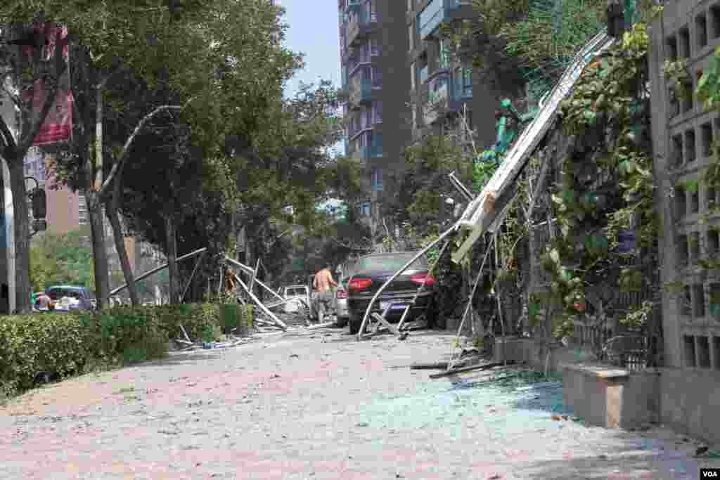 天津爆炸事故现场,核心爆炸区周围多座居民楼窗户被震碎,高速公路桥梁受损,多辆大货车被炸翻,小汽车起火或被砸,多名当地居民仍逗留在事故现场。(美国之音记者东方拍摄)