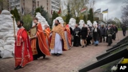 Orthodox priests hold a ceremony to honor Chernobyl firefighters to mark the 36th anniversary of the Chernobyl nuclear disaster in the capital Kyiv, Ukraine, April 26, 2022. Firefighters sculptures are covered with bags to protect against the Russian shelling.