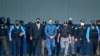 El expresidente hondureño Juan Orlando Hernández (C) es escoltado por el Ministro de Seguridad Ramón Sabillon y fuerzas de seguridad hacia un avión de la Agencia Antidrogas de Estados Unidos (DEA), durante su extradición a Estados Unidos el 21 de abril de 2022. 