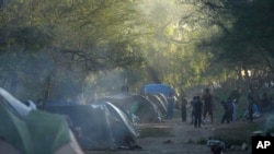 Migran Venezyelyen jwe foutbol nan yon kan yo tabli bo kote yon rivye nan Matamoros, Meksik, 22 Desanm, 2022. 