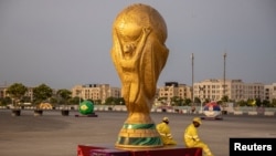 Pekerja duduk di samping replika Piala Dunia di luar Stadion Lusail jelang Piala Dunia, di Lusail, Qatar, 10 November 2022 REUTERS/Marko Djurica
