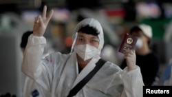 资料照：通过曼谷机场内一名身穿防护服的中国学生举起中国护照。（2020年4月21日）