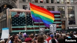 FILE - A rainbow flag flies as people protest U.S. President Donald Trump's announcement that he plans to reinstate a ban on transgender individuals from serving in any capacity in the U.S. military, in Times Square, in New York City, July 26, 2017. 