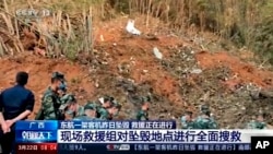 En esta imagen tomada de un video del CCTV de China, soldados registran el lugar donde se estrelló un avión en el condado de Tengxian, en la región autónoma de la etnia zhuang de Guangxi, en el sur de China, el martes 22 de marzo de 2022.