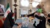 Une mère vote lors de la présidentielle iranienne dans un bureau de vote du consulat iranien, à Najaf, en Irak, le 18 juin 2021. 