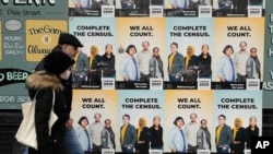 FILE - People walk past posters encouraging participation in the 2020 Census in Seattle's Capitol Hill neighborhood, April 1, 2020.