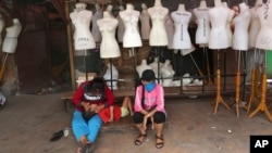 Mujeres sentadas frente a maniquíes en un mercado textil cerrado debido a la pandemia de coronavirus, en Yakarta, Indonesia, el 30 de abril de 2020.