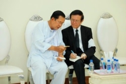 FILE - Cambodian Prime Minister Hun Sen, left, talks with dissolved main opposition Cambodia National Rescue Party leader Kem Sokha at the mourning ceremony for Sen's mother in-law, in Phnom Penh, Cambodia, May 5, 2020.