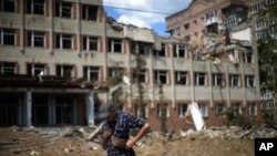 Un residente de pie junto a un edificio muy dañado en un bombardeo ruso enfrente de su casa en Bakhmut, en el este de Ucrania, el martes 24 de mayo de 2022. (AP Foto/Francisco Seco)
