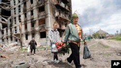 Stanovnici Marijupolja prolaze pored stambene zgrade razorene u ruskom bombardovanju