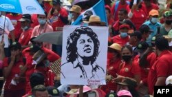 Empleados del Sindicato de Trabajadores del Instituto Hondureño del Seguro Social sostienen un cartel de la líder indígena asesinada Berta Cáceres durante la manifestación del Primero de Mayo (Día del Trabajo) en San Pedro Sula, Honduras, el 1 de mayo de 2022.
