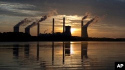 FILE - In this June, 3, 2017, file photo, the sun sets behind Georgia Power's coal-fired Plant Scherer, one of the nation's top carbon dioxide emitters, in Juliette, Ga. (AP Photo/Branden Camp, File)
