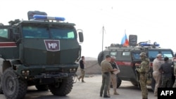 A handout picture obtained from the Syrian Kurdish North Press Agency on Oct. 24, 2019 shows Russian military police troops standing next to their armored vehicles in the northeastern Syrian city of Kobane on Oct. 23, 2019. 