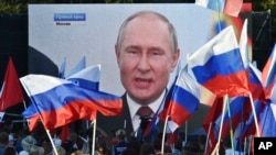 People in Sevastopol, Crimea, watch on a large screen on September 30, 2022, as Russian President Vladimir Putin delivers a speech after Moscow carried out sham referendums to justify annexing four regions of Ukraine. (Associated Press)