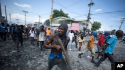 Un manifestante porta un pedazo de madera como si fuera un rifle durante una protesta antigubernamental, el 3 de octubre del 2022, en Puerto Príncipe, Haití. (AP Foto/Odelyn Joseph)