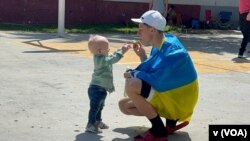 Un padre hace burbujas con su hijo el 6 de abril de 2022 en el polideportivo Benito Juárez en Tijuana, México, que fue convertido en un centro de refugiados para ucranianos. [Foto: VOA / Celia Mendoza]