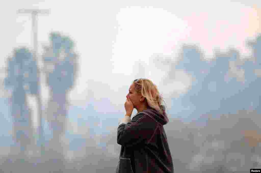 A woman reacts as the Woolsey Fire burns in Malibu, Calif., Nov. 9, 2018. The fire destroyed dozens of structures, forced thousands of evacuations and closed a major freeway.