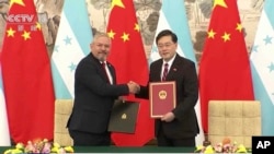 En esta imagen tomada de la televisora china CCTV, los cancilleres de Honduras, Eduardo Enrique Reina, a la izquierda, y China, Qin Gang, se dan la mano después de una ceremonia de firma en Beijing, el 26 de marzo de 2023.