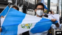 Un hombre sostiene una bandera guatemalteca durante una demostración para exigir al gobierno que ponga fin a las medidas de confinamiento. Mayo 2020.