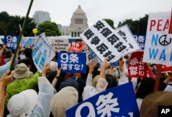 FILE - In this Aug. 30, 2015 file photo, protesters hold anti-war placards in front of the National Diet building during a rally in Tokyo. Japan holds an election on July 10, 2016, for the upper house of parliament that could affect the country’s future.