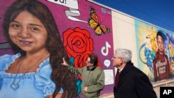 El artista Abel Ortiz muestra al secretario de Justicia de EEUU, Merrick Garland, a la derecha, los murales que recuerdan a las víctimas de la masacre de 2022 en la escuela en Uvalde, Texas, el 17 de enero de 2024. 