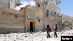 FILE - Civilians make their way on a street littered with the rubble of buildings damaged by air strikes in Aleppo, May 14, 2014.