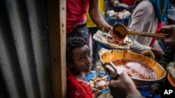 FILE - Elena, 7, center, lines up with other displaced Tigrayans to receive food donated by local residents at a reception center for the internally displaced in Mekelle, in the Tigray region of northern Ethiopia, May 9, 2021.