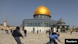 Un camarógrafo cae el suelo perseguido por un policía isralí durante enfrentamientos en el complejo de la mezquita de al-Aqsa en Jerusalén el 10 de mayo de 2021.