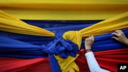 Un partidario de la oposición sostiene una tela con los colores de la bandera venezolana antes de un mitin con el líder opositor Juan Guaidó en el barrio Montalbán de Caracas, Venezuela, el 11 de enero de 2020.