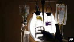 FILE - A nurse manager checks on IV fluids while talking to a COVID-19 patient at Providence Holy Cross Medical Center in Los Angeles, Dec. 13, 2021. 