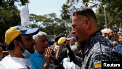 Un miembro de la Policía Nacional Bolivariana habla con trabajadores públicos durante una protesta exigiendo mejores salarios en medio de una inflación altísima, en Venezuela, el 16 de enero de 2023.