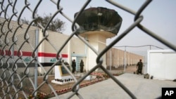 FILE - Guards stand at the entrance of Abu Ghraib prison on the outskirts of Baghdad, Iraq, Feb. 21, 2009. 