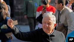 El presidente de México, Andrés Manuel López Obrador, muestra su tarjeta de identificación después de votar en un referéndum sobre si debe terminar su mandato de seis años o continuar hasta el final, en la Ciudad de México, el domingo 10 de abril. 2022. (Foto AP/Eduardo Verdugo)