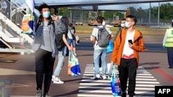 FILE - This handout picture taken on November 30, 2020 and released by Charles Darwin University shows foreign students disembarking from an international flight at Darwin Airport in Darwin. (Photo by JULES / Charles Darwin University / AFP)