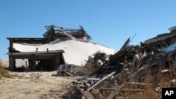 The ruins of an oceanfront home destroyed by Superstorm Sandy is scattered next to an existing home in Mantoloking N.J., Tuesday, Oct. 15, 2013. 