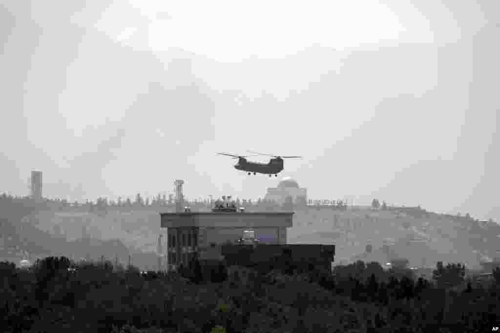 ឧទ្ធម្ភាគចក្រ Chinook មួយគ្រឿងរបស់សហរដ្ឋអាមេរិកបើកនៅក្បែរស្ថានទូតសហរដ្ឋអាមេរិកក្នុងរដ្ឋធានីកាប៊ុល ប្រទេសអាហ្វហ្កានីស្ថាន ថ្ងៃទី១៥ ខែសីហា ឆ្នាំ២០២១ ខណៈដែលរថយន្ដការទូតនានាដឹកមន្ត្រីការទូតសហរដ្ឋអាមេរិកចេញពីបរិវេណស្ថានទូតនេះ។
