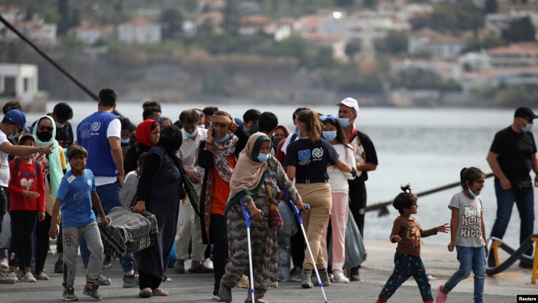 FILE - Refugees and migrants from the destroyed Moria camp wait to board a ferry that will transfer them to the mainland, at the port of Mytilene on the island of Lesbos, Greece, Sept. 28, 2020. 