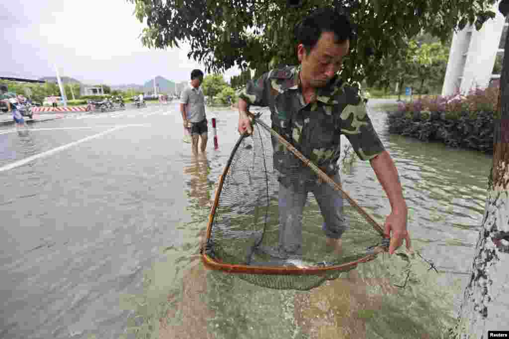 A man fishes on a flooded street after Typhoon Haikui hit Taizhou, Zhejiang province, China, August 8, 2012.