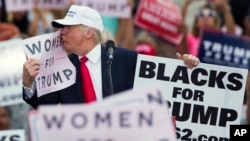 Republican presidential candidate Donald Trump kisses a "Women for Trump" sign during a campaign rally, Wednesday, Oct. 12, 2016, in Lakeland, Florida. 