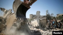 Palestinians gather as rescue workers search for victims from under the rubble of a house, which witnesses said was destroyed by an Israeli airstrike, in Beit Lahiya, northern Gaza Strip, Aug. 25, 2014. 