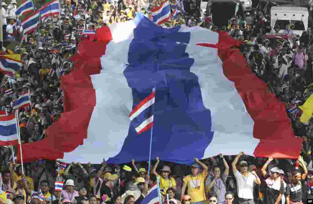 Demonstran anti pemerintah membawa bendera nasional Thailand raksasa pada saat melakukan unjuk rasa di Bangkok.